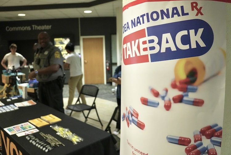 VCU Police officer stands in student commons talking to students. There is a sign for national Take Back day.