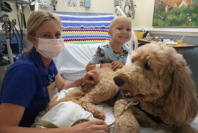 Margaret smiles as Elsa sits on the bed of a child in the hospital.