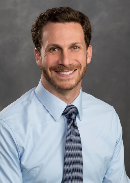 Dr. Silverstein in a blue button up shirt with navy blue pattern tie.