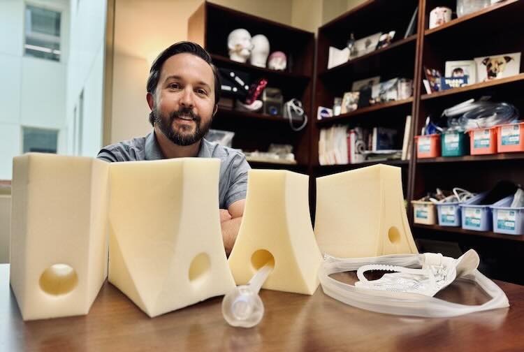 Dr. Grey sitting behind the a fecal management system flow positioning device model he co-developed.