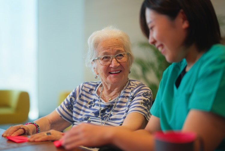 Older woman speaking with nurse in her home.