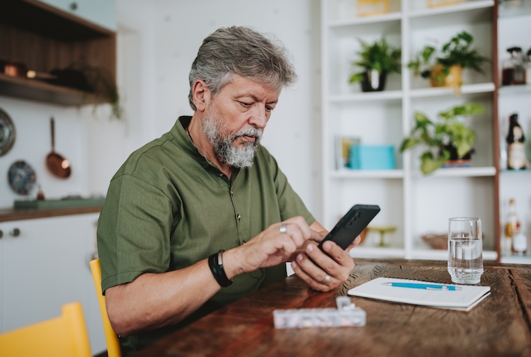 Older man looking at smart phone app to make sure he’s taking his medications on time.
