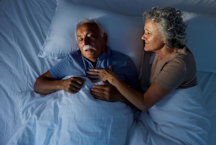 Woman trying to wake up man who is experiencing sleep apnea