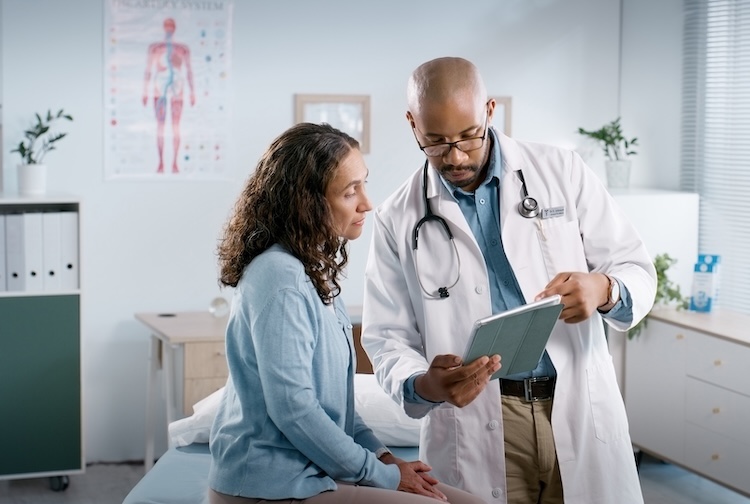 doctor speaks with patient while holding a tablet to go over medical information