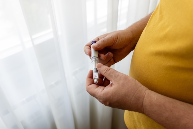 Close-up of hands preparing a GLP-1 injection pen, a treatment for weight management and diabetes.