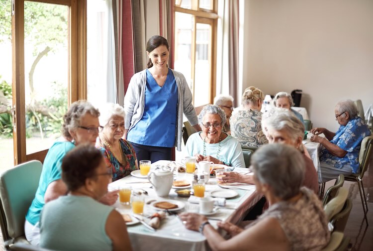 A group of older women around a table in conversation.