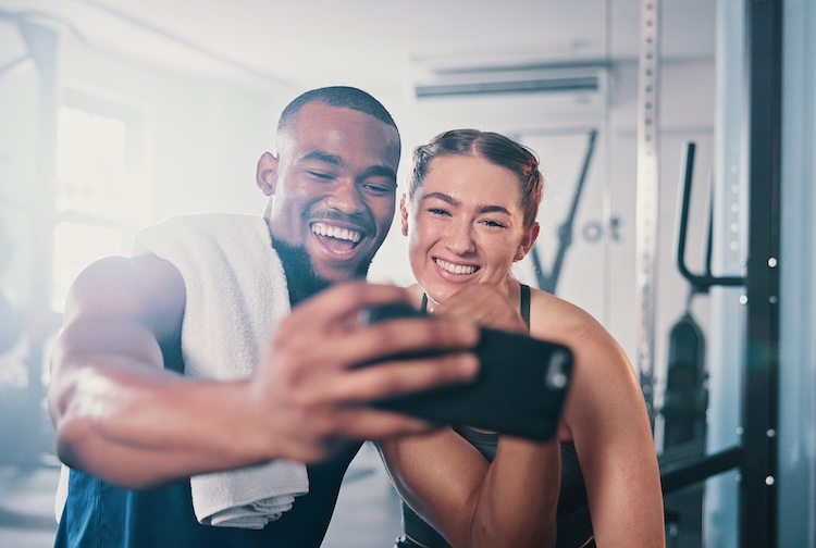 Man and woman in the gym, taking a selfie on a phone camera