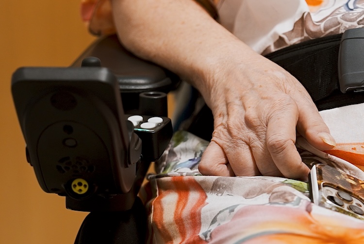 Woman sitting in wheel chair with her hand near a cellphone