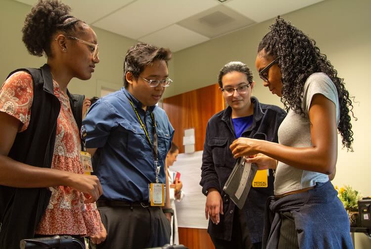 Group of students in a huddle discussing the escape room set-up