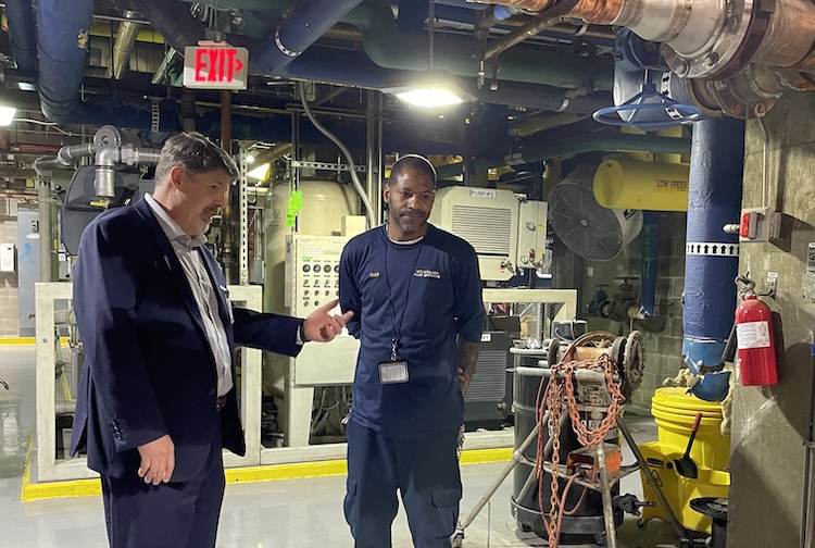 Man in suit talking to another man in the basement of the hospital