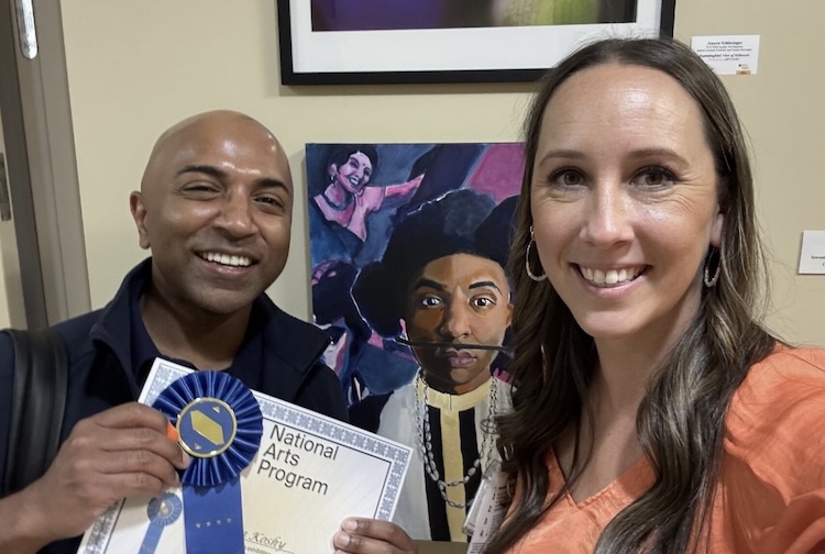 Man holding award next to woman as they take a selfie.