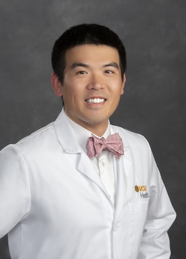 Dr. Yu wears a white medical coat and red bow tie