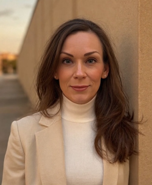 Jill is standing outside in a cream colored suit.