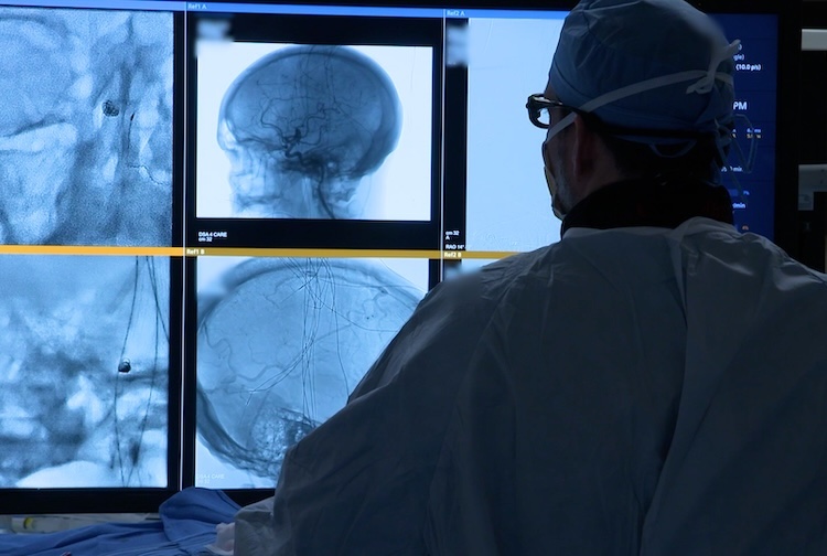 Surgeon looking at live image of patient while navigating through a vein
