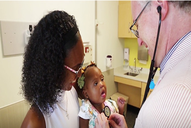 Mother holding her daughter during doctors visit.