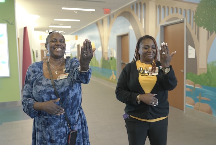 Ladies standing next each other with hands out laughing