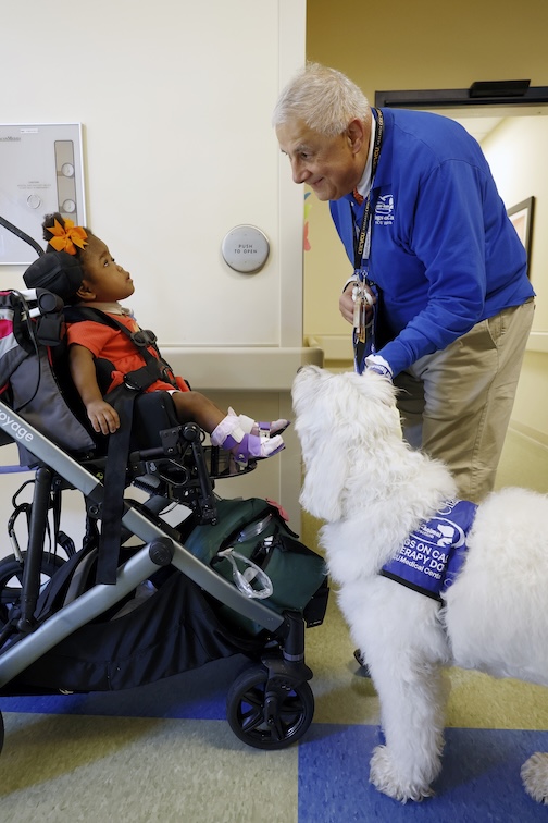 Dr. Levy smiles as a little girl in a wheelchair looks up at him