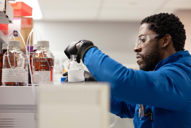 Researcher wearing blue jacket works with test tubes
