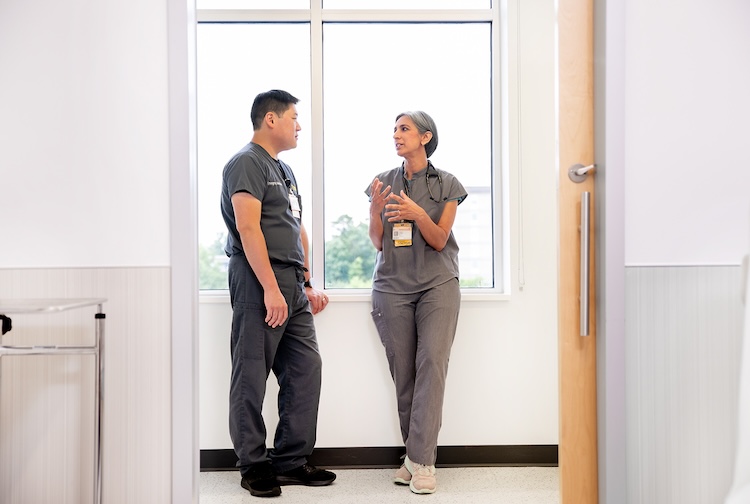 Two VCU Health clinicians talking to each other near a window