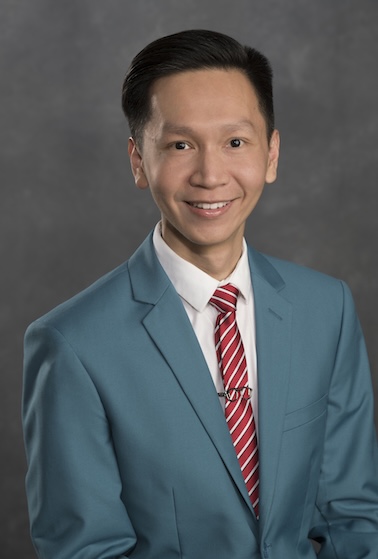 Dr. Ching wears a blue suit and red tie