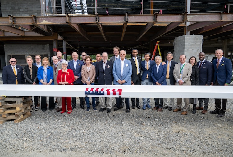 VCU Health, VCU and community members stand behind a building beam