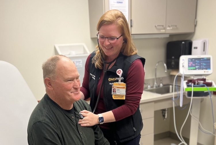 A physician’s assistant checks a patient’s heartbeat.