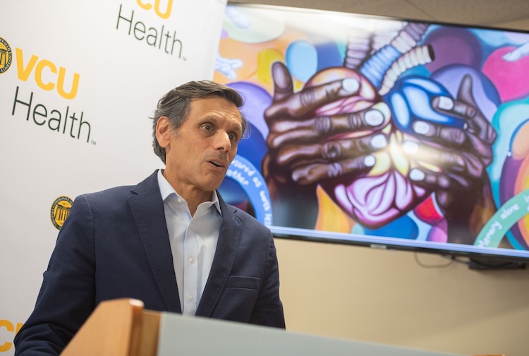 President Michael Rao wears a blue suit jacket while speaking to a crowd