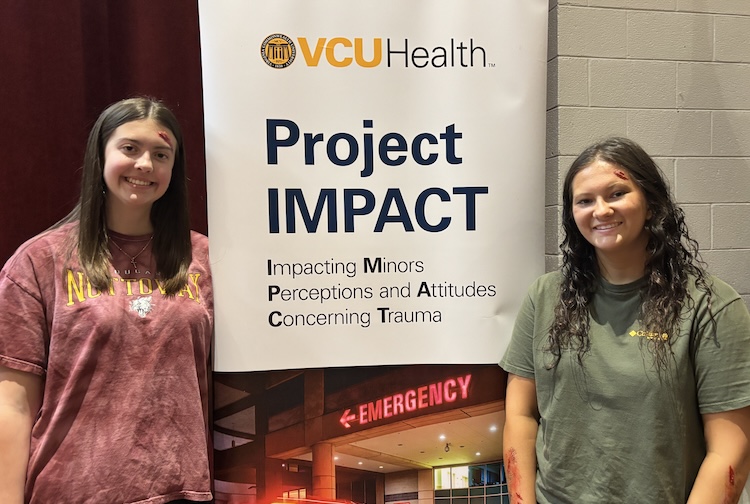 Two high school seniors pose next to a VCU Health sign for Project IMPACT.