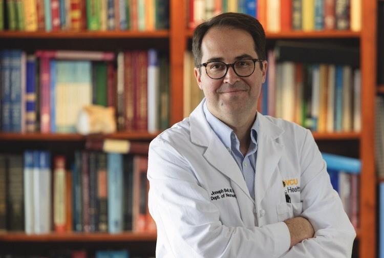 Dr. Bell in his medical white coat in a library.