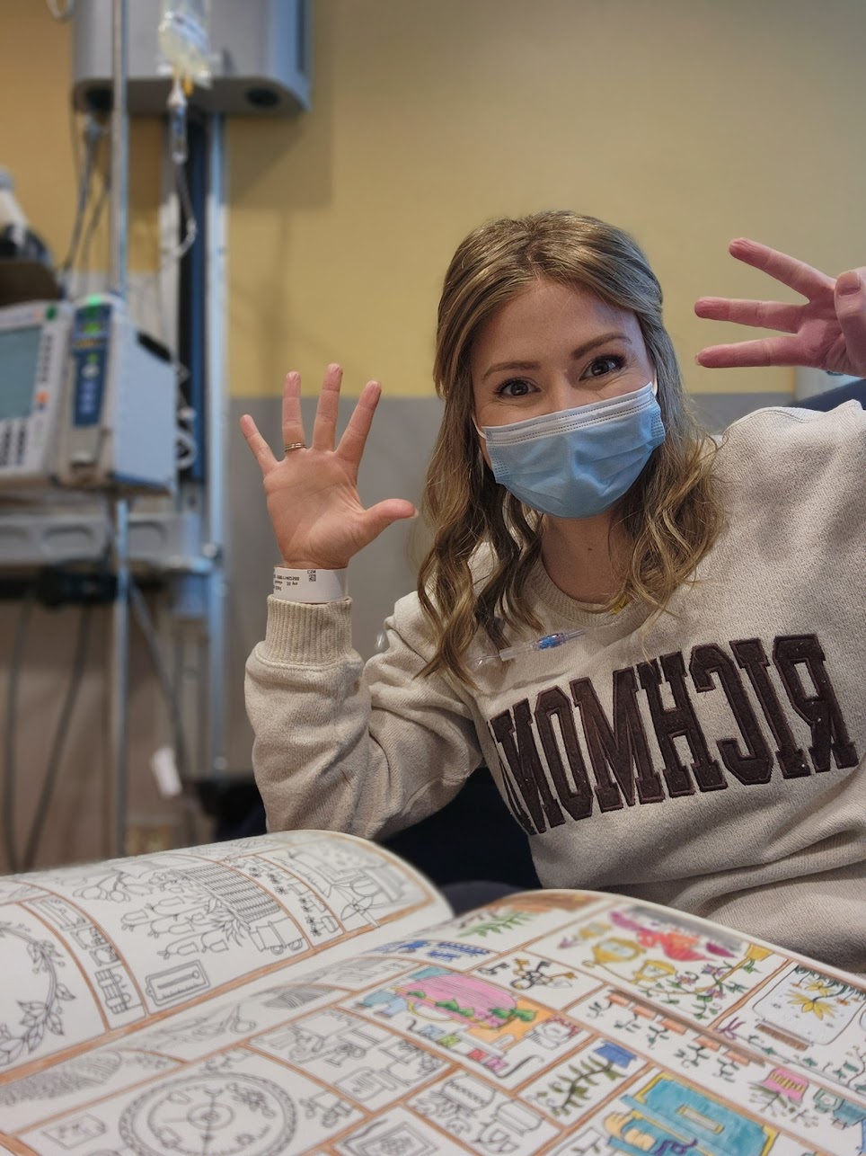 VCU Health breast cancer patient counting the number of chemo treatments she's finished. She is wearing a facemask, a wig and has a coloring book at chemo.