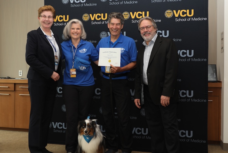 VCU researchers stand with two Dogs on Call volunteers and therapy dog