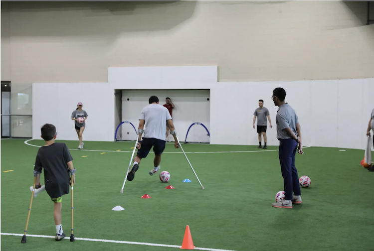Participants playing amputee soccer in an indoor field.