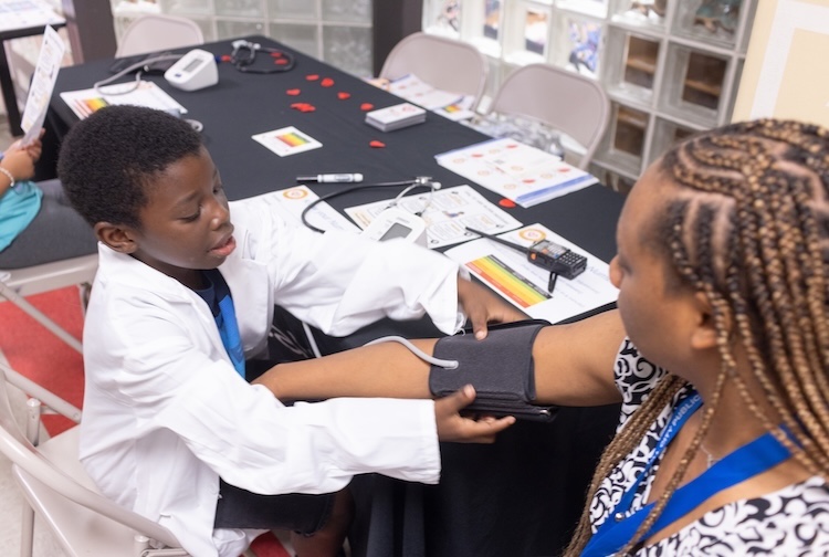 Little boy puts a blood pressure monitor cuff on his teacher