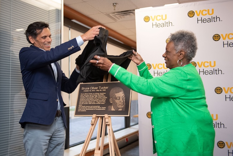 President Rao and Gayle Turner smile as they lift a cloth over the plaque