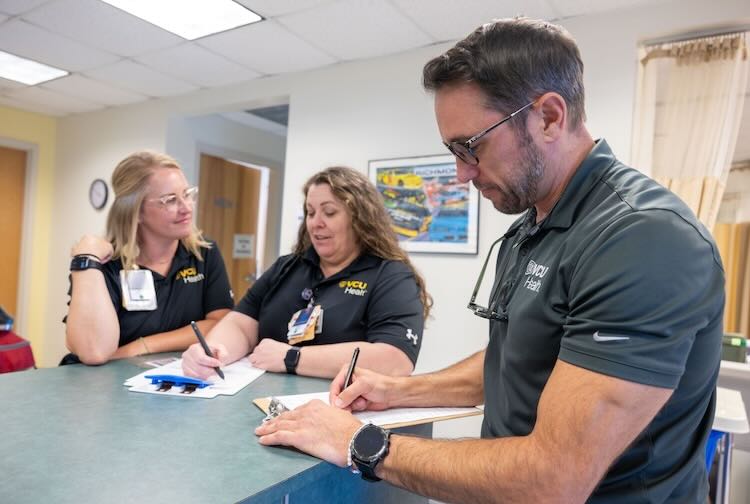 Dr. Tozer looks over paperwork while talking to two nurses at the infield care center.