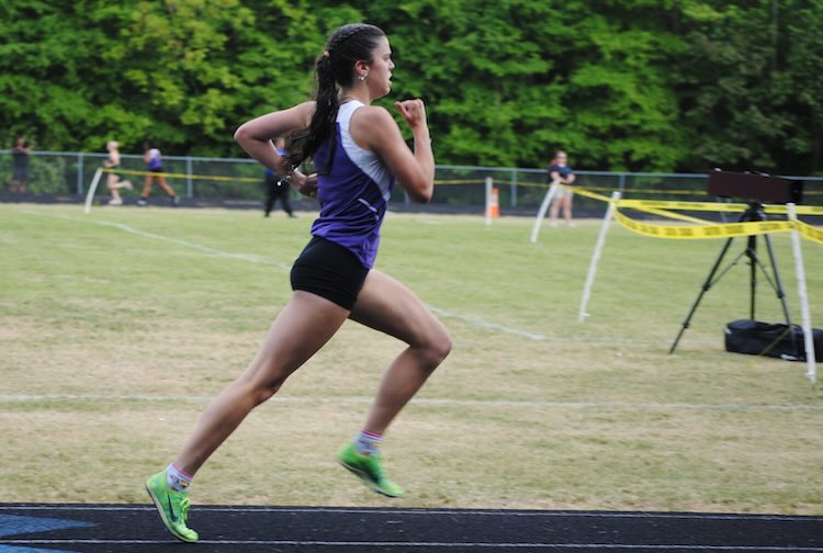Mackenzie running on a track in her track uniform