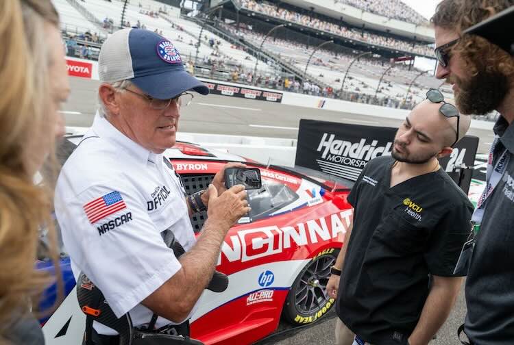 VCU Health emergency medicine physicians speaking with a NASCAR official on the side of the track.