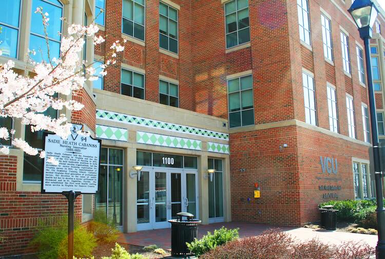 Brick building with flowering bushes and trees around it