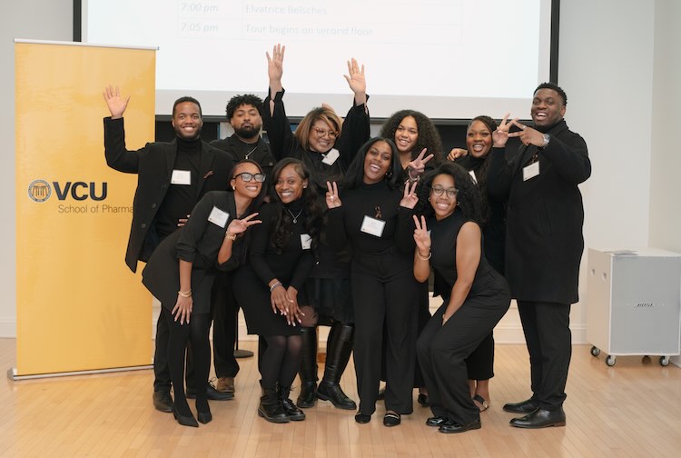 Students from the Black Student Pharmacist Organization dress in all black pose together for a photo.