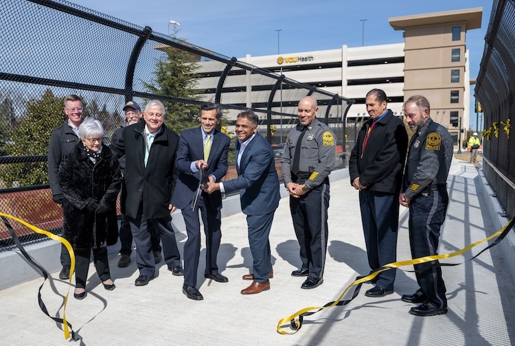 Leaders from VCU Health, VCU, the City of Richmond and the Virginia Department of Transportation cut ribbon to the newly installed pedestrian bridge.