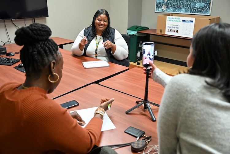 Woman films with her phone as a Hume-Lee team member talks