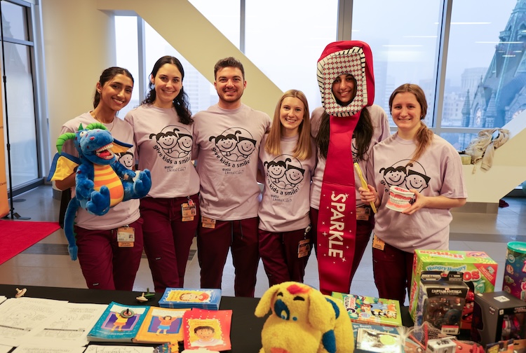 Group of VCU students stand together near a table with games for kids