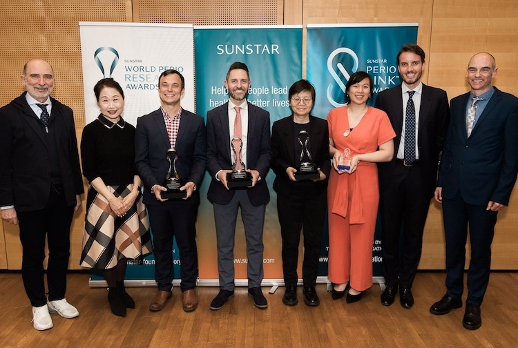 Group standing together in business attire holding awards
