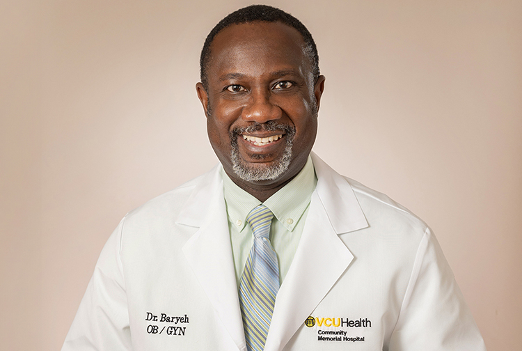 A physician in a white lab coat smiles at the camera.