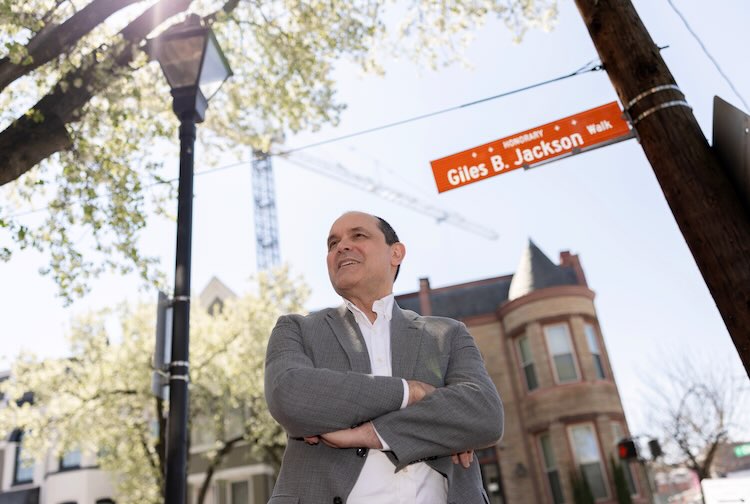 Beyers standing outside at the corner of the street with arms folded.