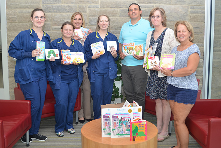 A group of health care workers and teachers hold books inside a hospital lobby.