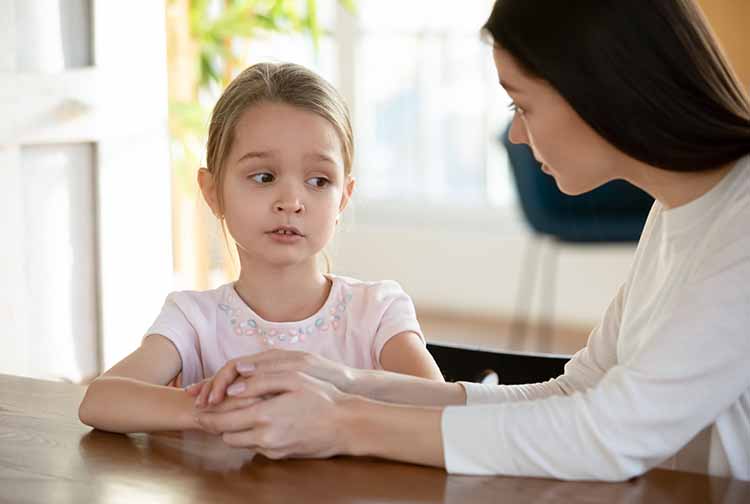 Mother speaking to young daughter, who looks scared