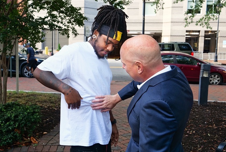 Patient turns to the side as doctor touches his side, examining the scarring from his liver transplant (above the shirt).