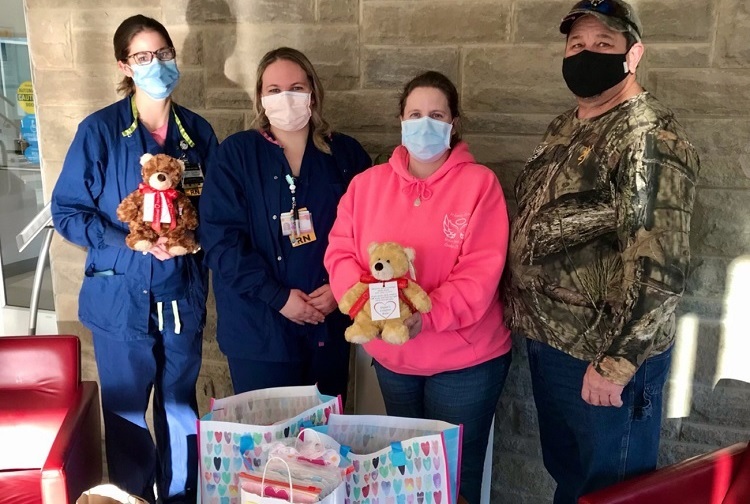 Sarah Carlton and Hilary Tackett accept donations from Shannon and Tracy Armes for newborns and their families