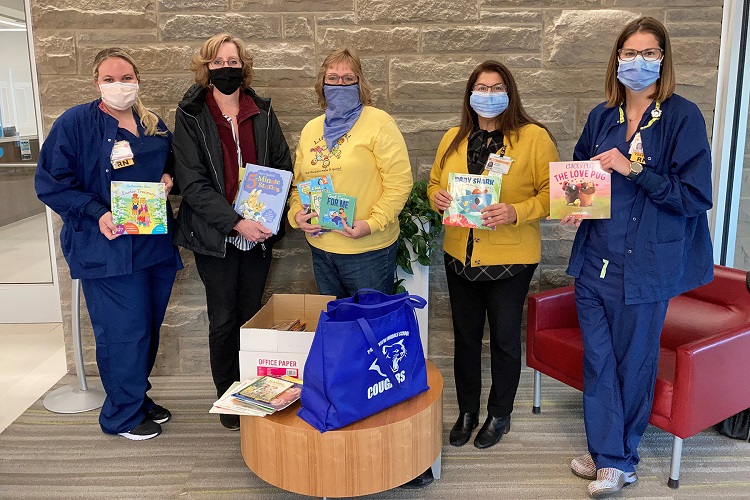 Members of the Alpha Pi Chapter of Delta Kappa Gamma pose pose with CMH birthing center nurses holding children's books